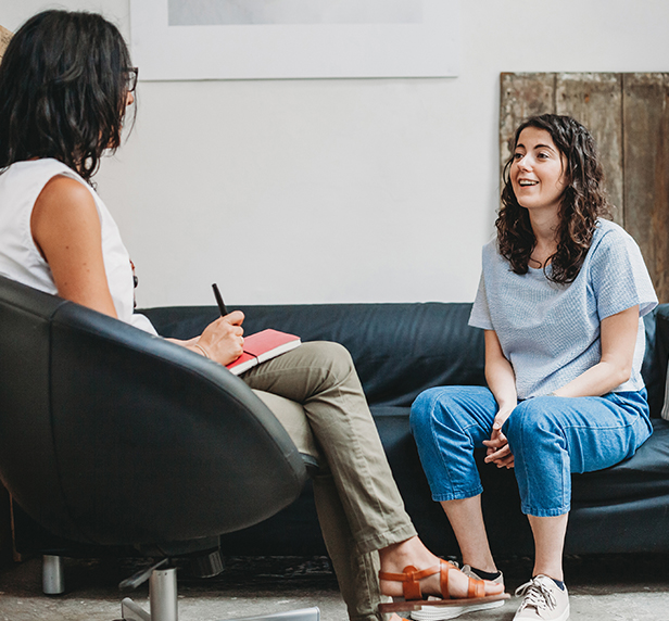 A teen sits and talks with her therapist about adjustment problems.