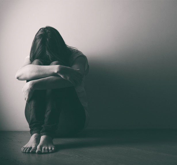 A women suffering from Premenstrual Dysphoric Disorder sitting in a ball.