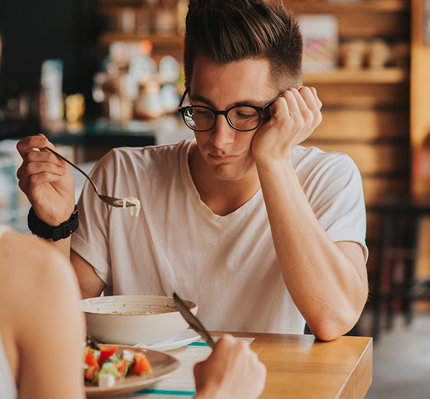 A man looks like he's struggling with an eating disorder, as he barely touches his food.