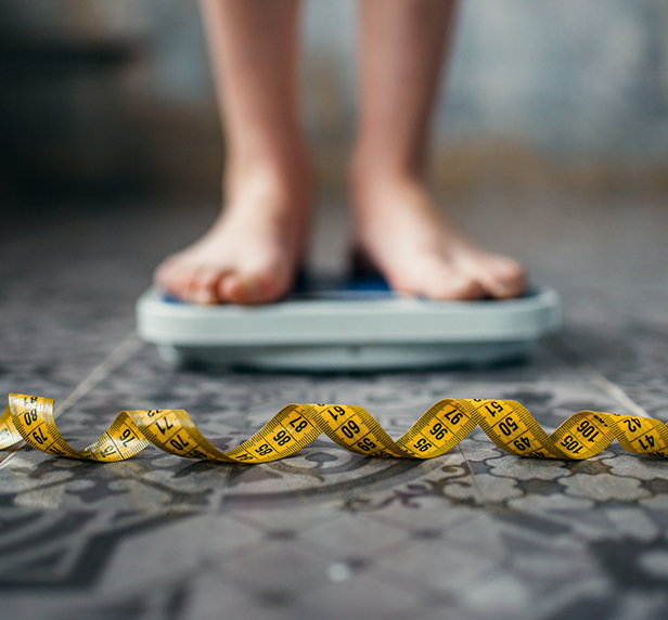 a women with a tape measurer and a scale, she's suffering from Anorexia Nervosa