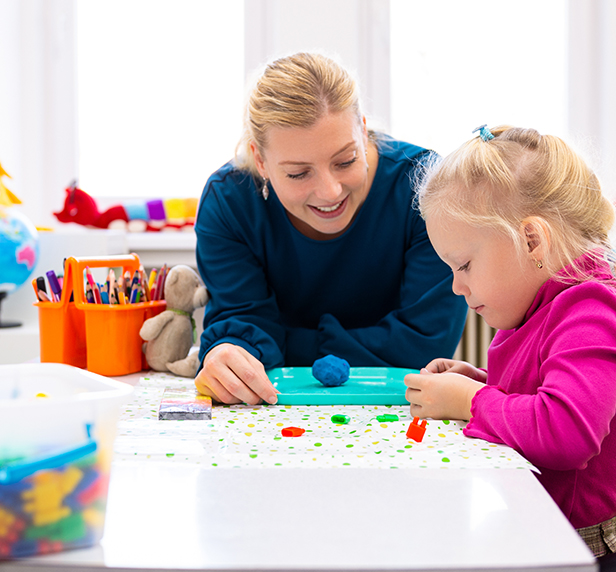 A therapists plays with a child while also talking about school concerns.