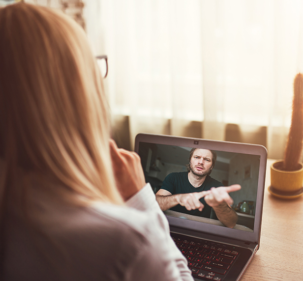 A therapist and her patient have a teletherapy session on her laptop.